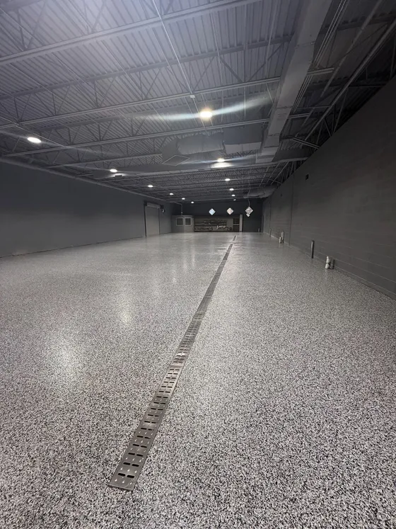 Large commercial space with a gray speckle epoxy floor and trench drain