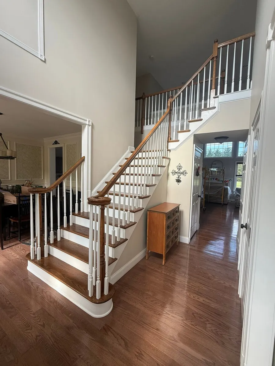 Two-story foyer with a curved oak staircase after a full interior repaint and refinish