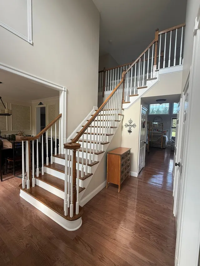 Two-story foyer with a curved oak staircase, freshly painted walls and refinished railings