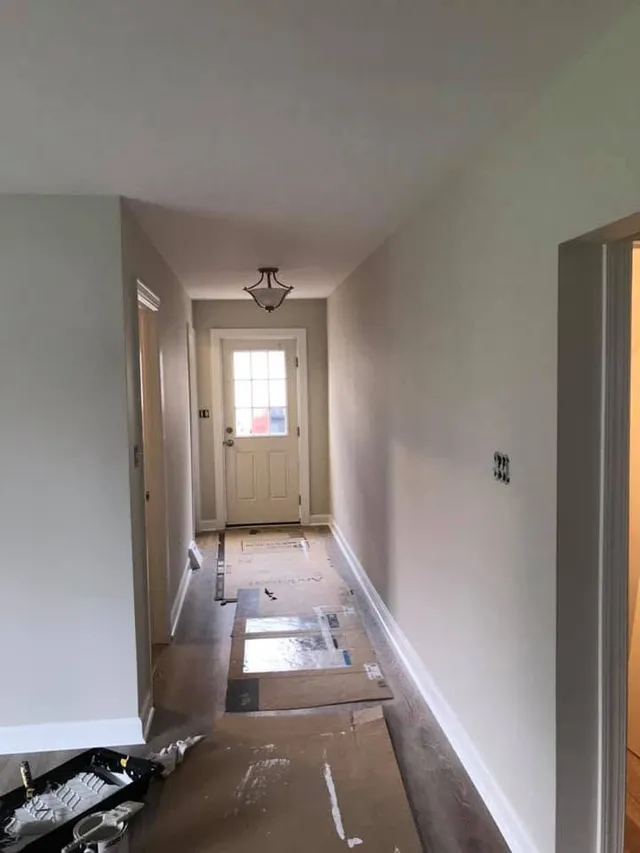 Hallway mid-paint job with drop cloths and painting supplies
