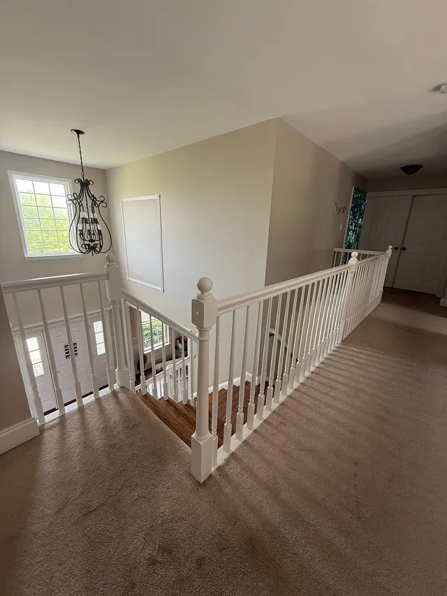 Upstairs landing with chandelier, painted trim and railings, finished
