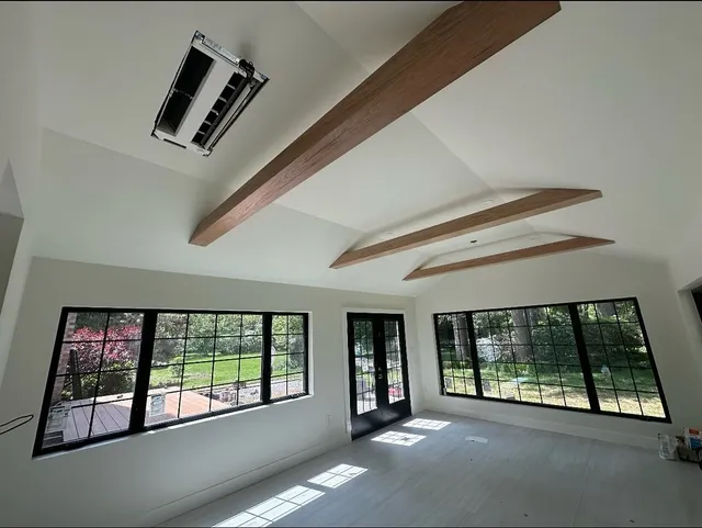 Sunroom with a vaulted white ceiling, exposed wood beams, and black-grid windows