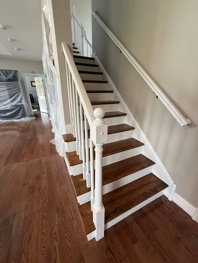 Staircase from below during a refinish, walls protected with plastic sheeting